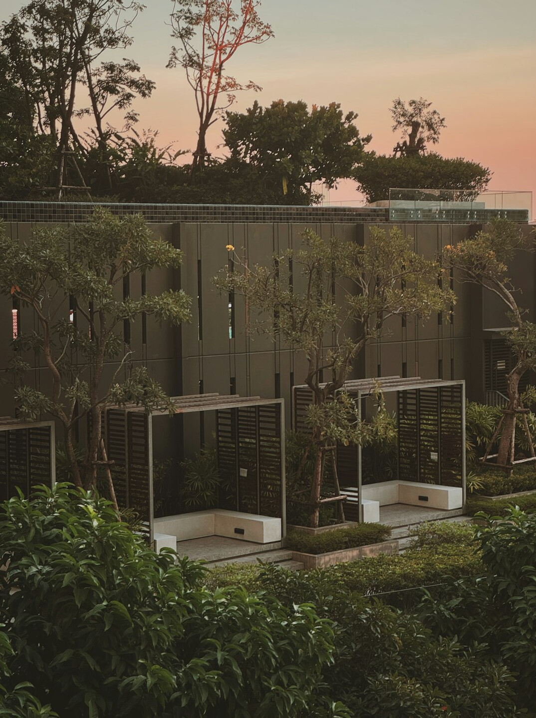 Modern villa facade with large windows and manicured garden at dusk